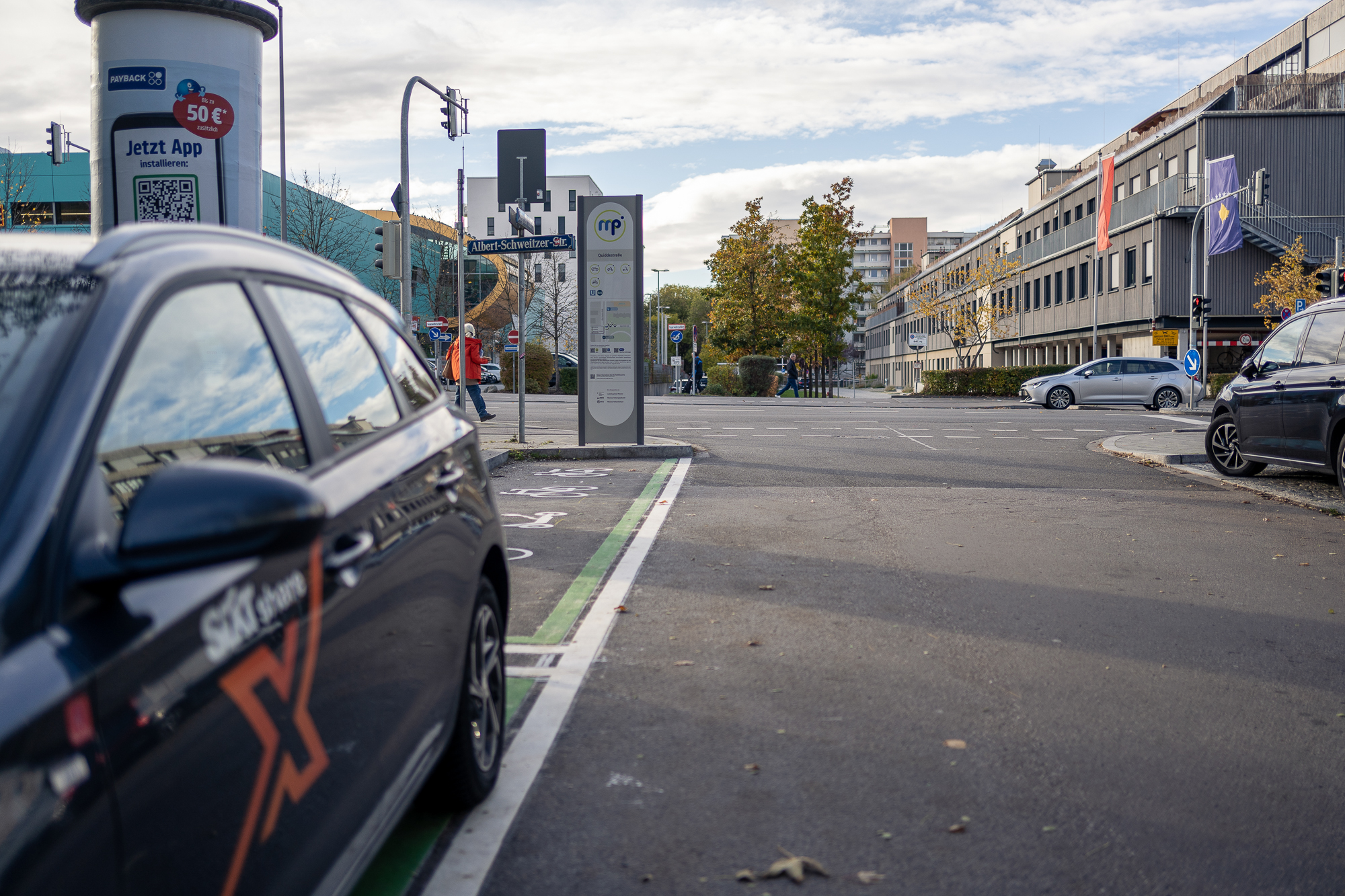 Foto des Mobilitätspunkts an der U-Bahnstation Quiddestraße. Es ist ein Carsharing Auto zu sehen, dass auf dem Stellplatz parkt.